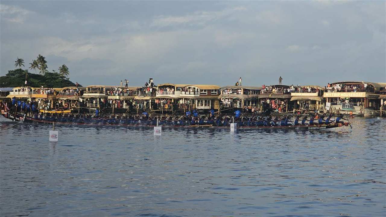 Snake boats racing past houseboats on Punnamada Lake