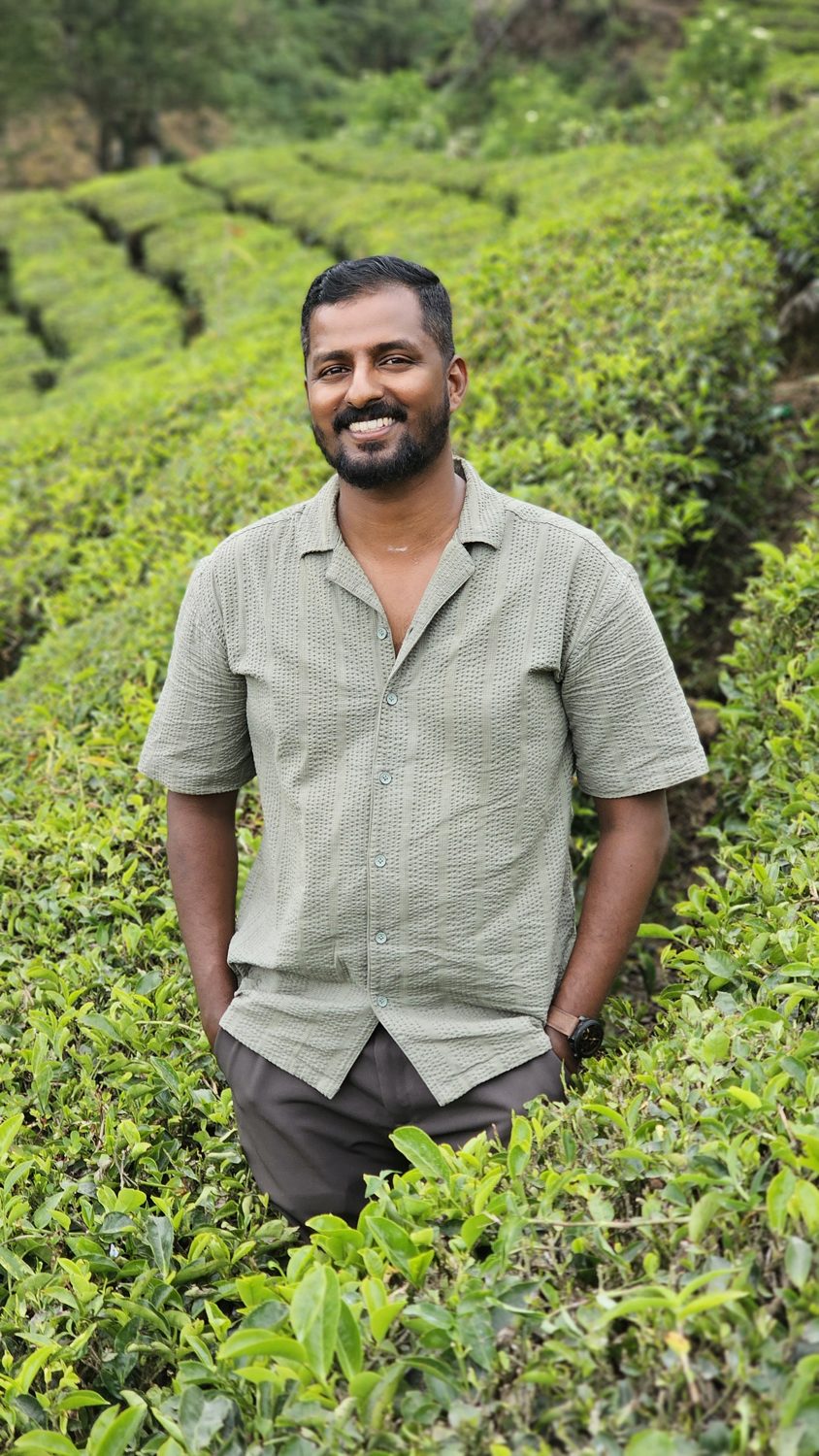 Abhijit, founder of Enroute Kerala, smiling among the tea bushes in Munnar